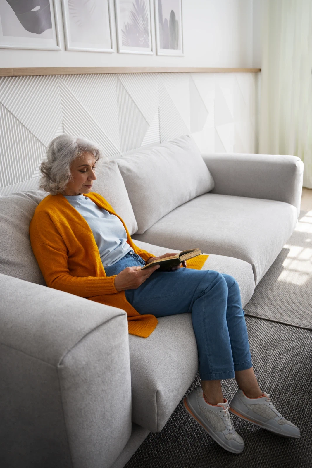 Oudere vrouw leest ontspannen op de bank in haar woning